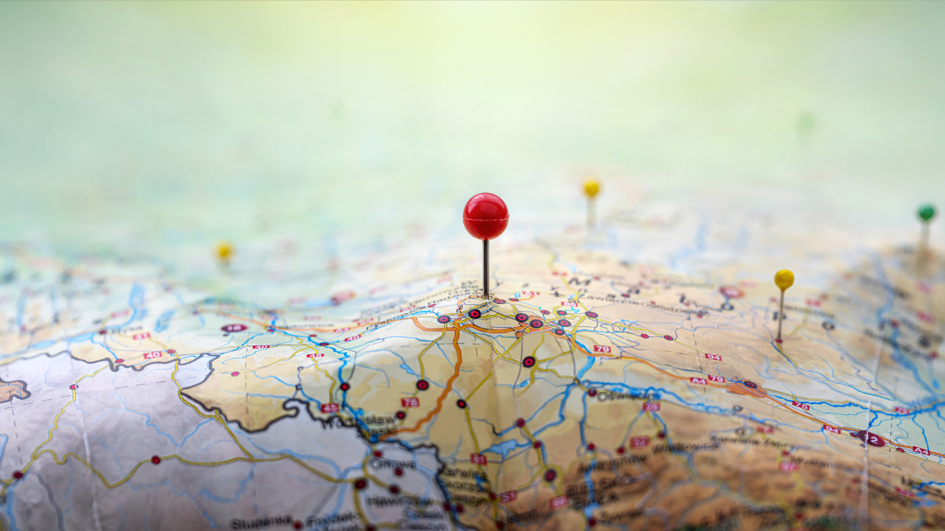 Pins on a geographic map curved like mountains. Pinning a location on a map with mountains. Adventure, geography, mountaineering, hike and travel concept background.